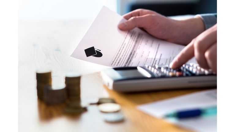 Man counting college savings fund, tuition fee or student loan with calculator. Education price and expenses concept. Money and papers on table.