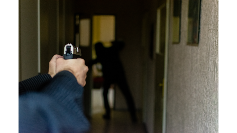 HD stock photographyof a action portrait of serious young detective, special agent, holding gun pointing the weapon, involved in shooting, entering in the the hallway in some bulding with caution, looking for and arresting a criminal.