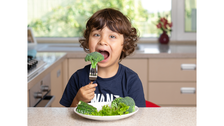 Young boy eating broccoli