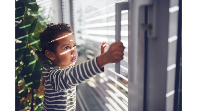 Little boy opening the window at home.