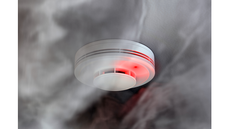 Dire alarm smoke detector with red LED indicator on ceiling