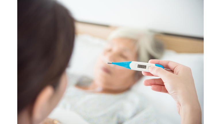 Nurse hand holding thermometer with high temperature result