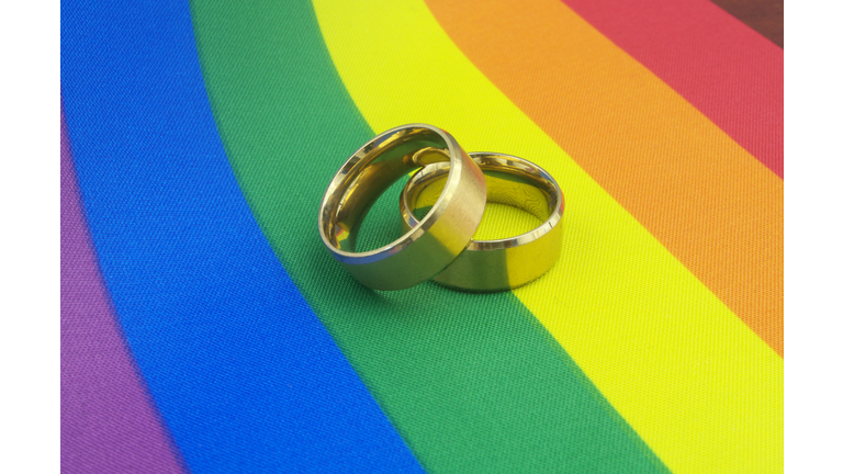 Gold wedding rings on LGBT pride flag.