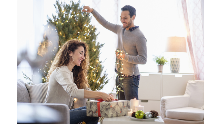 Couple decorating for Christmas in living room