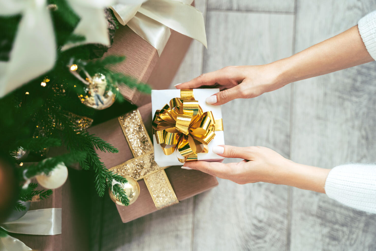 Soft woman hands putting gift box under the Christmas tree
