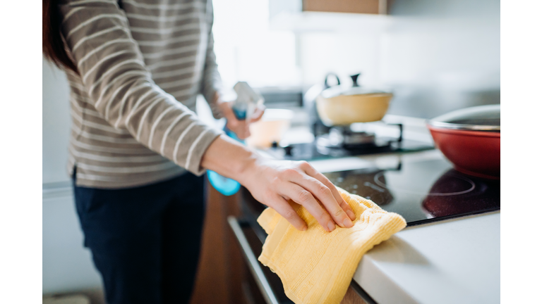 Cropped shot of a young woman cleaning the kitchen counter with cleaning spray and cloth at home during the day