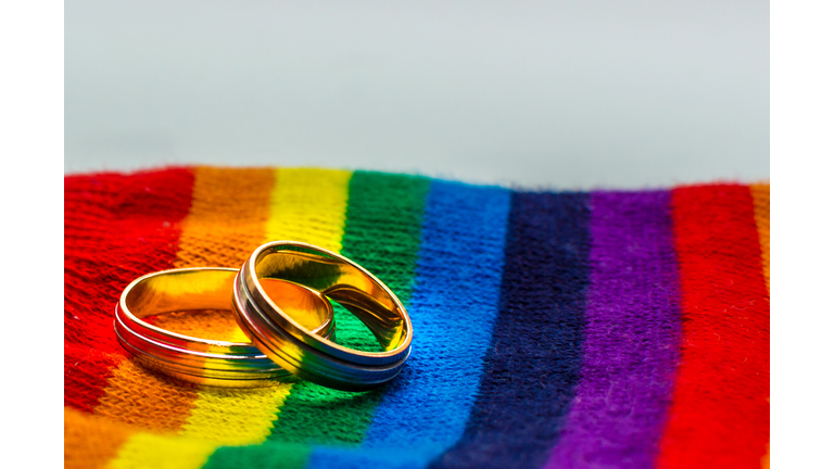 Two wedding rings on the fabric colors of the rainbow. Concept same-sex marriage.