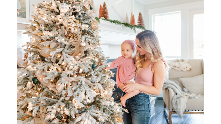 Mother Holding baby daughter by christmas tree