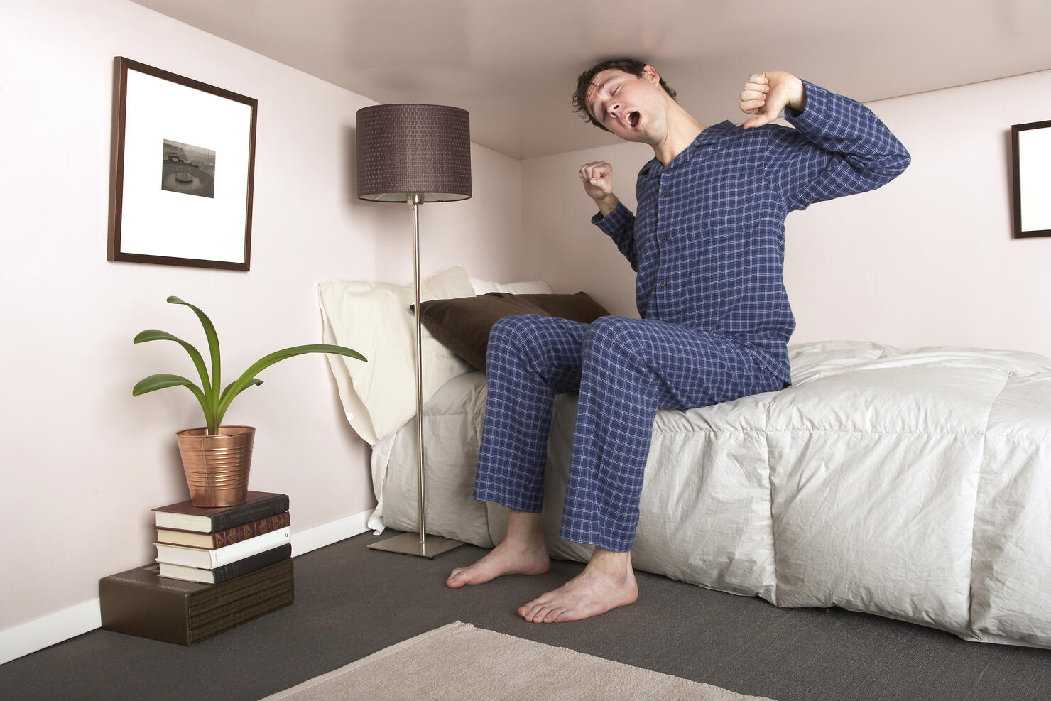 Man sitting on bed stretching in miniature bedroom