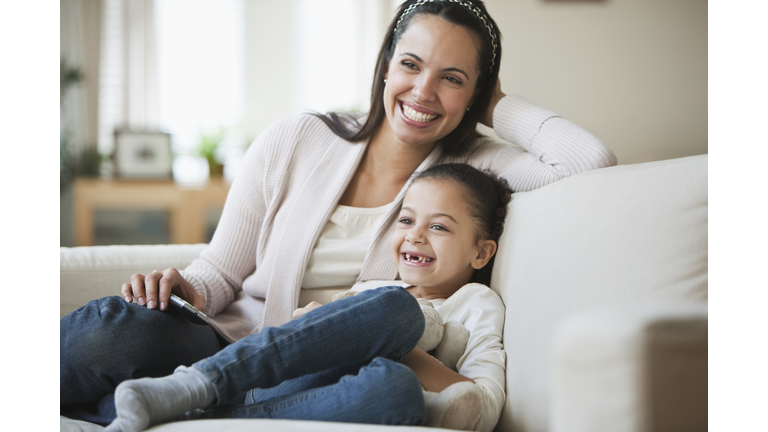 Hispanic mother and daughter watching television