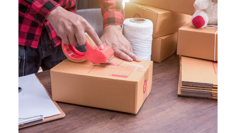 young hand woman prepareing package to be sent on wooden floor