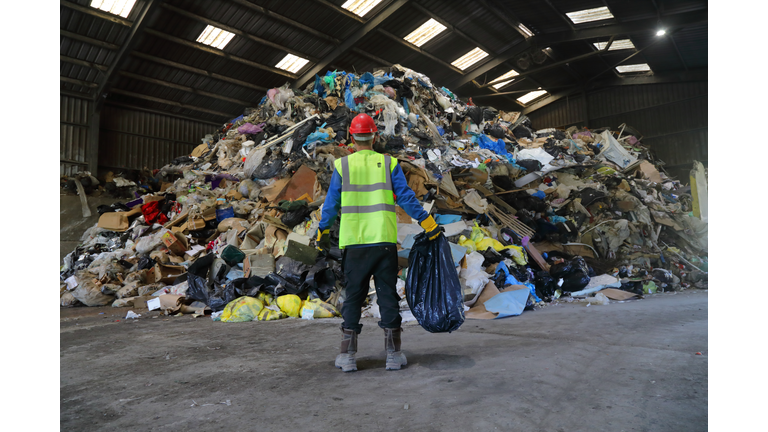 Man holding bag of rubbish at rubbish tip