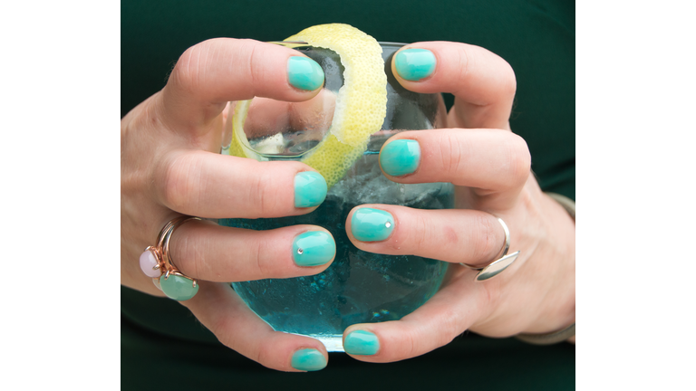 Woman's hand holding Cocktail  with green nails