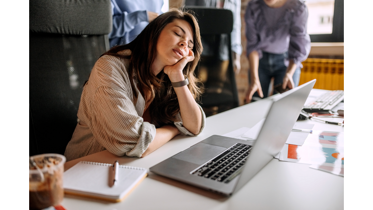 Young tired businesswoman sleeping at the office desk