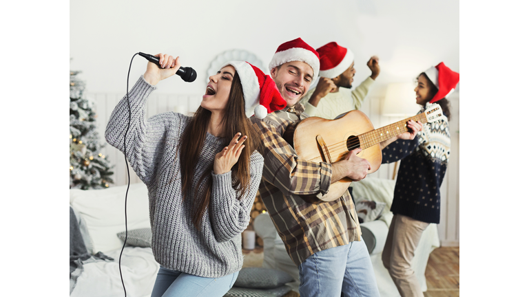 Happy friends singing together and playing on guitar