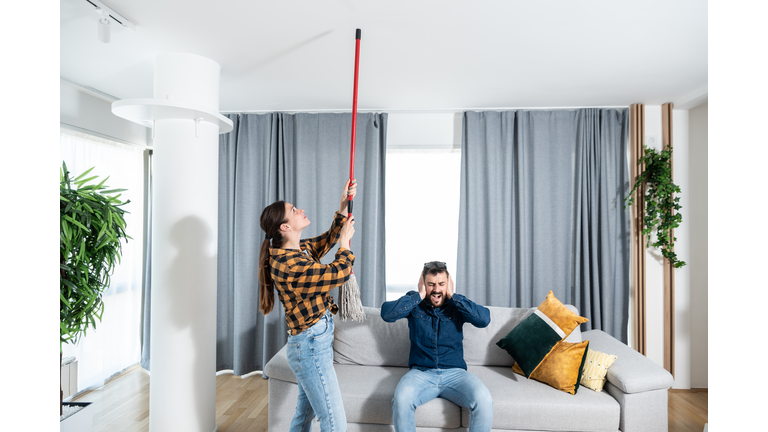 Young couple stares at the ceiling and yells because a neighbor upstairs is having a party with loud music or renovating an apartment and workers are drilling with heavy tools. Nise pollution concept