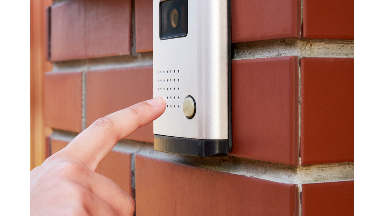 The female hand presses a button doorbell with camera and intercom