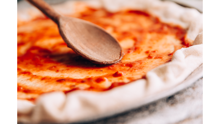 Spreading tomato sauce on pizza pan