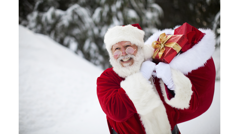 Cheerful Santa Claus Walking in Winter Snow with Christmas Gifts