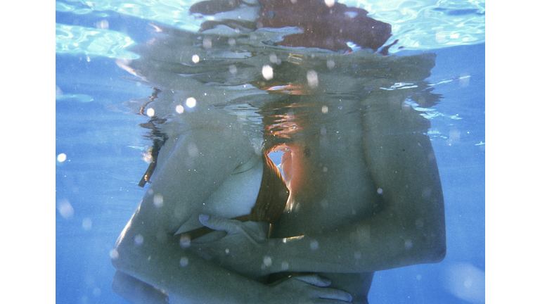 Couple embracing, mid-section, underwater view