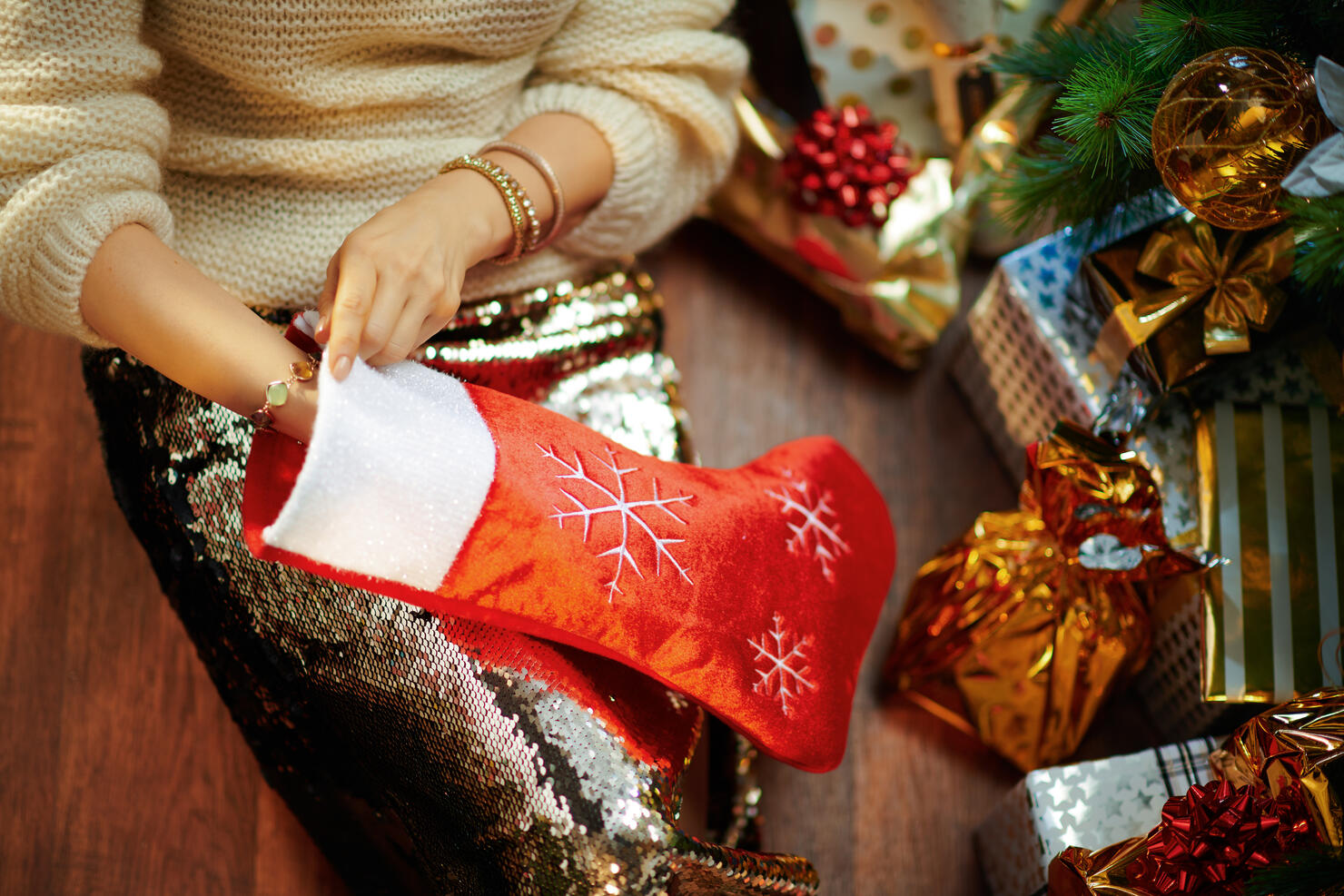 young woman takes something out of red Christmas stocking