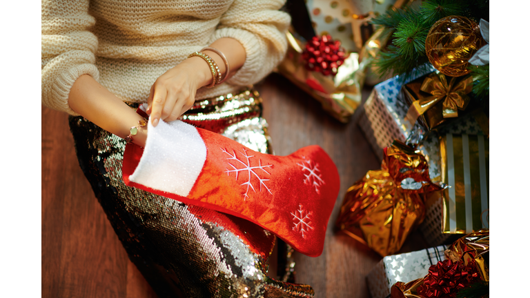 young woman takes something out of red Christmas stocking