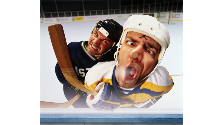 Ice hockey player checking opponent on to glass wall (Composite)