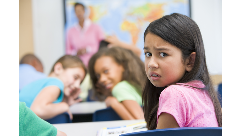 Student in class being bullied by students in background (selective focus)