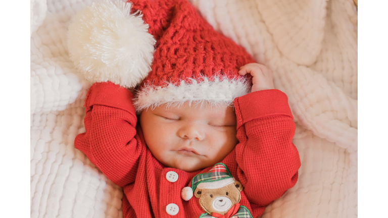 Sleeping newborn baby boy dressed in a cozy red Christmas outfit