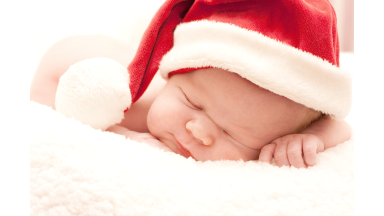 A sleeping newborn baby wearing a Santa hat