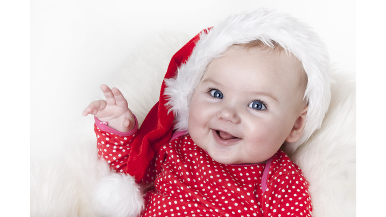 Smiling baby girl in red outfit and Santa hat