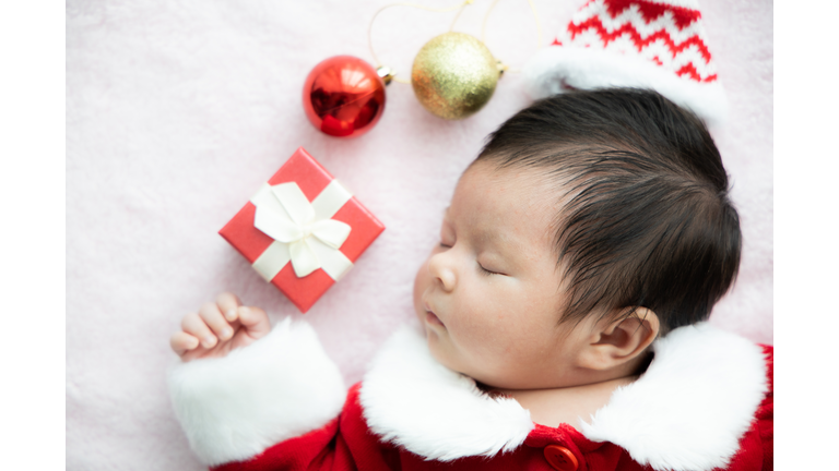 Sleeping newborn baby dressed in Santa suit