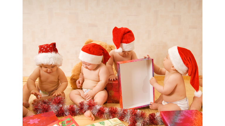 Group of adorable toddlers in Christmas hats packing presents