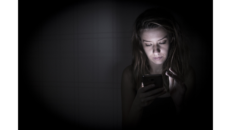 Lonely woman texting on smartphone at home bedroom at night