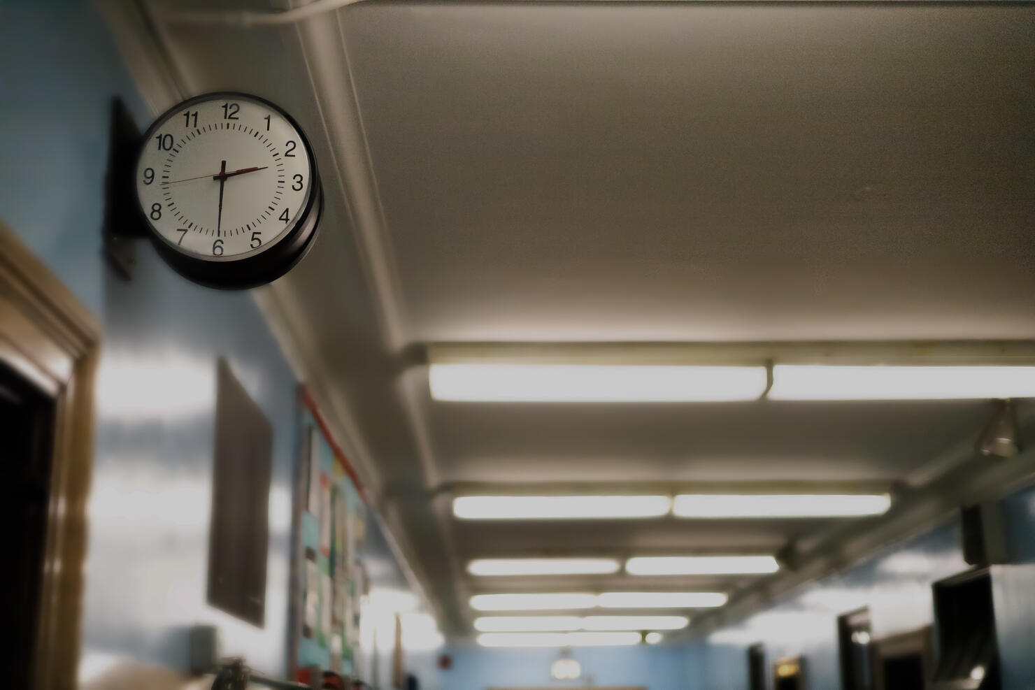 partial darkened view of school corridor with defocused exit sign in the background