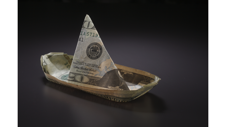 Close-Up Of Paper Boat Made With Currency Over Black Background