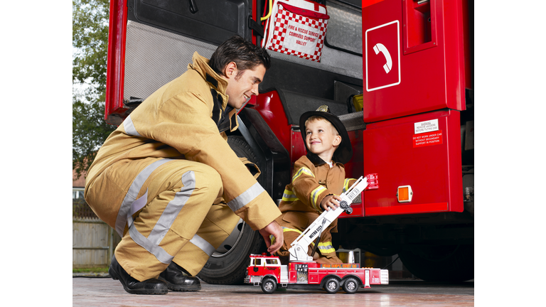Firefighter playing with boy (4-5), smiling