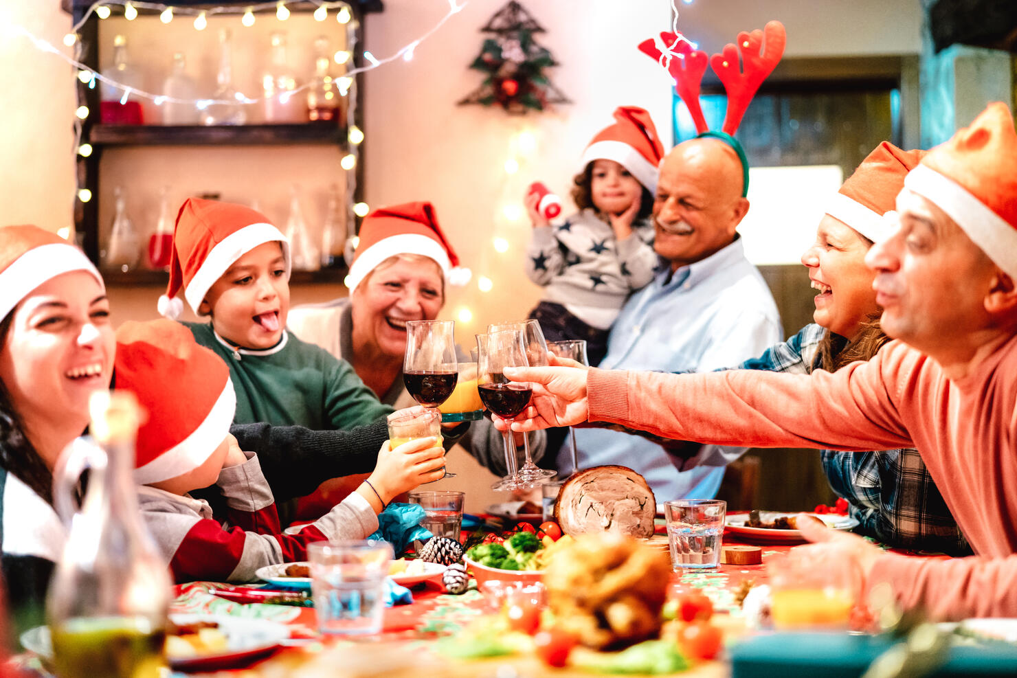 Big multi generation family toasting at christmas dinner feast - Winter holiday x mas concept with parents and children eating together at home supper reunion - Warm vivid filter with focus on glasses
