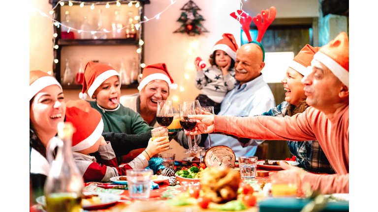 Big multi generation family toasting at christmas dinner feast - Winter holiday x mas concept with parents and children eating together at home supper reunion - Warm vivid filter with focus on glasses