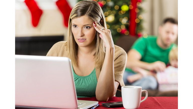 Concerned woman looks at her bank account balnce at Christmastime