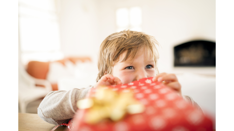 Happy boy opening Christmas present at home