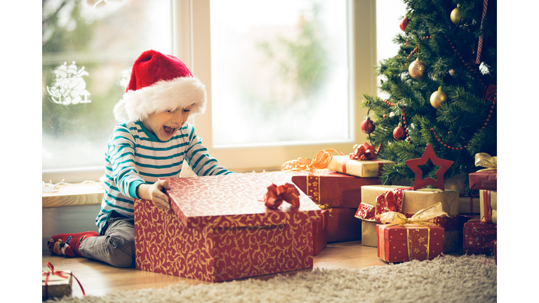 Surprised little boy opening Christmas present