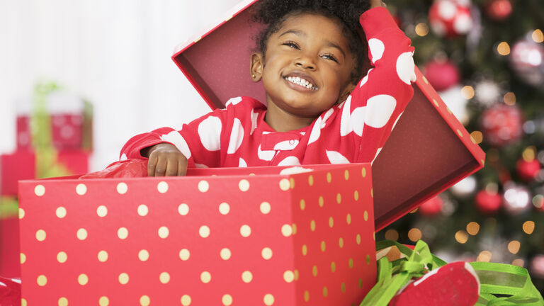 Smiling Black girl opening red gift box on Christmas