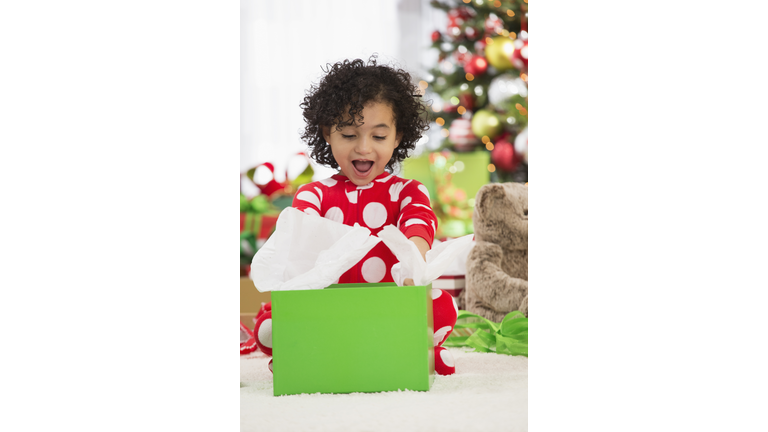 Hispanic girl opening Christmas gift