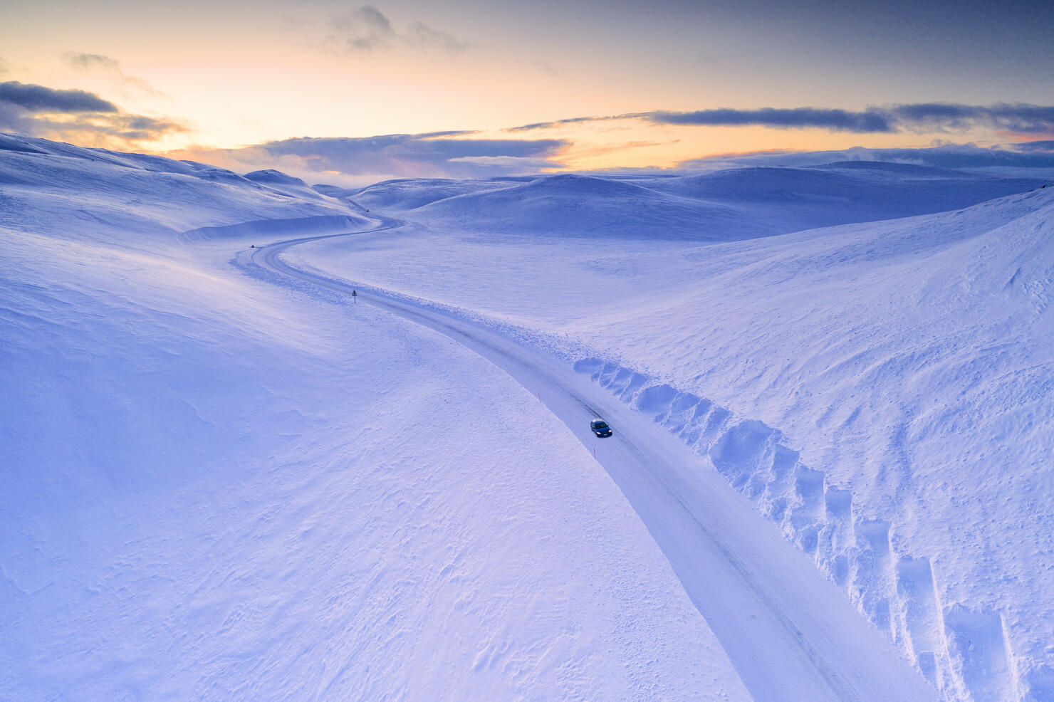 Car traveling on scenic road in the snow at sunset, Finnmark, Norway