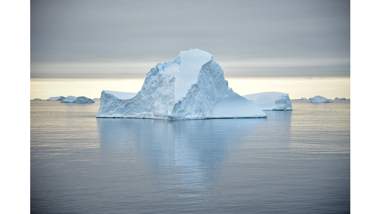 A dramatic pale iceberg reflected in the calm ocean.