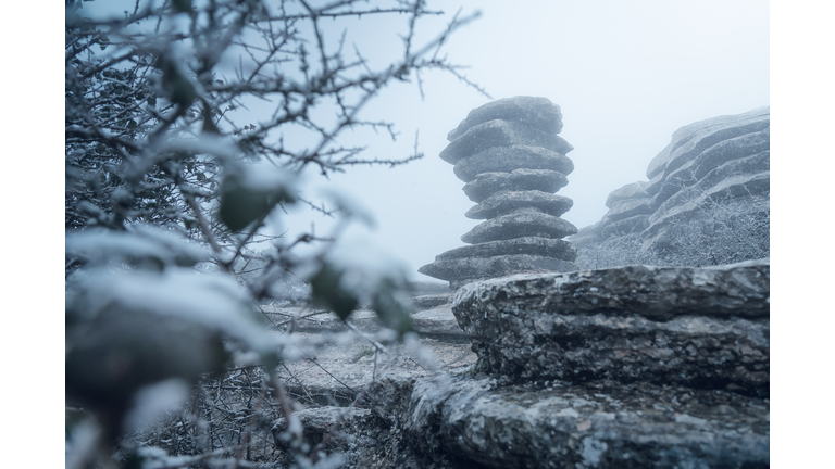 A snowy view of an unusual landform similar to a twisted screw or a pile of flat rocks.