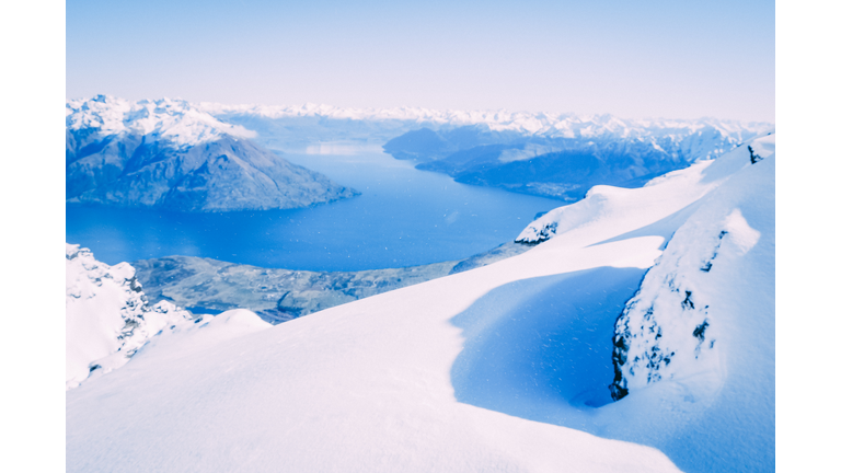 Snowcapped Mountains in the foreground with a blue lake starting at the center and moving to the rear.