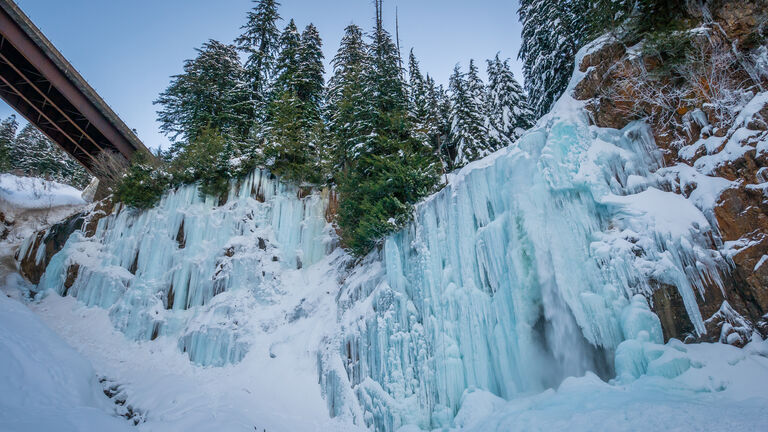 Frozen waterfall in a winter forest covered by snow.