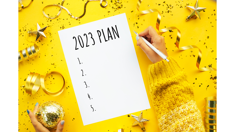 Writing New Year plan 2023. Merry Christmas coming concept. Decorations for Christmas tree on yellow background.